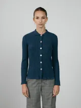 Camisa de punto acanalado color azul petróleo, con cuello tipo polo y cierre frontal de botones a tono. Presenta mangas largas y un ajuste entallado al cuerpo.