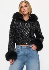 Chaqueta bomber negra con lentejuelas brillantes, cuello y puños de piel sintética. Presenta cierre frontal con botones y bolsillos delanteros con solapa.