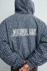 Cazadora cropped de corte holgado confeccionada en tejido texturizado con estampado de cuadros. Presenta cierre frontal con cremallera, capucha, mangas largas con puños elásticos y bolsillos frontales tipo canguro.