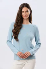 Buzo tejido de algodón color beige, de manga larga, con cuello redondo y delicados motivos bordados distribuidos en la prenda.