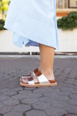 Sandalias bajas con base color suela, tiras anchas horizontales de cuero color marrón y plateado.