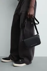 Bandolera negra con textura grabada, correa ajustable, monedero extraíble, compartimento principal con solapa imantada, bolsillo interno con cierre y bolsillo frontal con cierre.