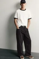 Pantalón barrel fit de mezclilla color verde militar, con efecto lavado, cinco bolsillos, cierre frontal con cremallera y botón, y detalle de pinzas en las rodillas.