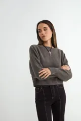 Sweater de punto negro, de corte holgado y diseño cropped, con cuello redondo y mangas largas.