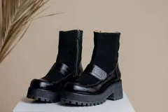 Botas negras de cuero con caña media, plataforma y hebilla decorativa.