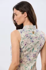 Camisa sin mangas de lino y algodón, con estampado floral en tonos violeta y verde sobre base beige, cuello camisero y cierre frontal de botones.
