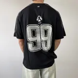 Remera oversize negra de manga corta, con ribetes blancos en los hombros y gran estampado trasero con el número 99 en blanco.