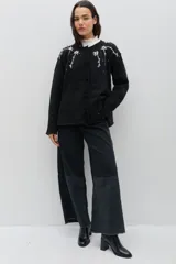 Saco de punto color negro con bordado floral artesanal en los hombros, cierre frontal con botones forrados y ajuste en la cintura.