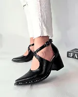Sandalias de cuero color negro, de diseño cruzado en el empeine con tira ajustable al tobillo, puntera fina y taco ancho de madera de 7 cm. Presenta costuras decorativas blancas a lo largo de la suela.