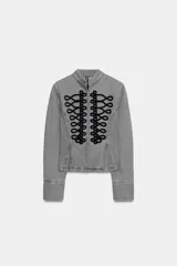Chaqueta de denim gris con cuello subido y manga larga. Presenta un diseño entallado con bajo en evasé y un llamativo bordado frontal de alamares en color negro. Cierre frontal con corchetes ocultos.