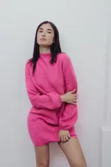 Vestido corto de punto color fucsia, con cuello alto y mangas largas amplias. Diseño holgado y cómodo.