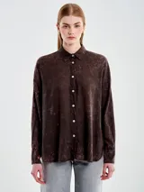 Camisa de manga larga con efecto acid wash en tonos marrón oscuro y rosado. Presenta cuello camisero y botones blancos en la parte frontal.