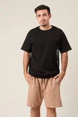 Bermuda de friza color beige claro, de corte suelto y largo a la rodilla, con cintura elástica y cordón de ajuste negro.