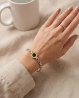 Pulsera de plata y lámina de oro 18k, con eslabones de cadena y un dije central redondo con piedra ónix negra y diseño de guarda griega.