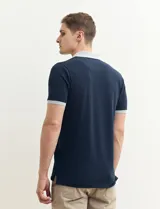 Remera manga corta color verde con cuello polo y bolsillo en el pecho. El cuello y los puños son de color azul marino.