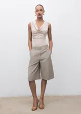 Body sin mangas de color beige, con escote drapeado y diseño entallado. Confeccionado en tejido elástico con tirantes anchos.