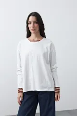 Remera de manga larga en color blanco, con calce relajado y diseño minimalista. Presenta un cuello redondo clásico y puños rectos, ideal para usar como prenda base en capas.