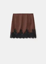Minifalda marrón con estampado de lunares negros y detalle de puntilla de encaje negro en el ruedo.