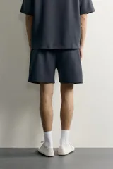 Bermuda estilo jogger de ajuste relajado, confeccionada en tejido interlock de algodón. Cuenta con cintura elástica ajustable con cordón, bolsillos frontales de vivo y diseño liso.