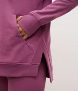 Buzo cerrado deportivo de corte oversized, color violeta, con cuello redondo, mangas largas con puños acanalados y bolsillo frontal funcional. Presenta detalles de encaje en los laterales y ruedo acanalado.