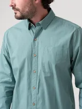 Camisa de manga larga RKF modelo Galiton, color verde, confeccionada en algodón orgánico. Cuenta con cuello camisero, cierre frontal con botones de madera, un bolsillo aplicado en el pecho con el logo bordado y sistema para arremangar las mangas.