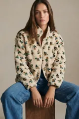 Campera de corderito con estampado floral, cuello alto y cierre frontal con botones a presión. Posee puños elásticos y un diseño de ajuste al cuerpo.