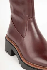 Bota corta de cuero sintético color negro, con punta redonda, cierre lateral y suela tipo tractor con plataforma de 6 cm.