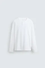 Camiseta de manga larga blanca, corte relajado, con cuello redondo y tapeta de botones (cuello panadero o henley).