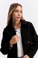 Campera corta de paño color negro, con cierre frontal metálico, cuello camisero y bolsillos frontales con solapa y botón metálico.