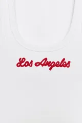 Musculosa de canalé blanca, con escote redondo y el texto "Los Angeles" bordado en rojo en el pecho.