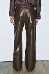 Pantalón de tiro medio, pierna recta, confeccionado en tejido efecto piel marrón oscuro con acabado arrugado. Presenta cinco bolsillos y cierre frontal con cremallera y botón.