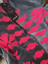 Chaqueta de terciopelo gris con bordados en fucsia de estilo suzani, con cuello mao y diseño abierto al frente.