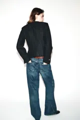 Blazer de corte entallado con cuello redondo, manga larga y hombreras. Presenta cierre frontal con botones dorados y una textura sutil en la tela.