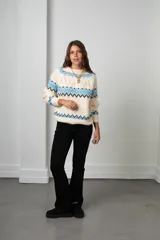 Buzo de tejido de punto con diseño nórdico, cuello redondo acanalado y mangas largas. Presenta un patrón geométrico en tonos celeste, negro y crema.