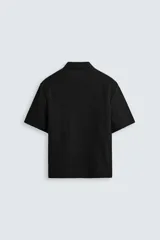 Camisa regular fit de manga corta confeccionada en tejido jacquard con estructura abierta y diseño geométrico. Presenta cuello solapa y cierre frontal con botones al tono.