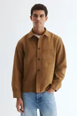 Sobrecamisa de H&M en tejido de efecto gamuza color marrón, con cuello inglés, cierre frontal de botones, un bolsillo en el pecho y mangas largas con puños abotonados.