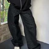 Jeans baggy negro de tiro medio con estampado animal print sutil de leopardo en tono sobre tono, corte amplio y relajado en las piernas.