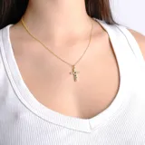 Collar dorado con dije de cruz adornado con piedras de colores.