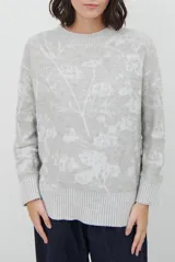 Buzo de tejido de punto con cuello redondo, mangas largas con puños acanalados y diseño estampado de flores en tonos rojos.