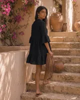 Vestido corto negro de lino con cuello mao, escote con botones, mangas tres cuartos con volados y falda con volado en el ruedo.