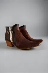 Botas cortas de cuero marrón jaspeado con detalles pintados a mano en tonos dorados, con taco cuadrado de altura media, punta fina y cierres laterales decorativos.