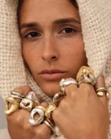 Anillo plateado con forma orgánica irregular y un agujero en el centro.