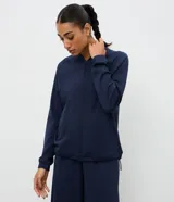 Campera deportiva de cuello alto con cierre frontal, mangas largas con puños elásticos y diseño de corte raglán. Presenta un estilo minimalista y funcional con cintura ajustable.