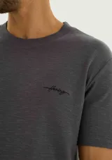 Remera gris de manga corta con textura tipo waffle y pequeño bordado en el pecho.