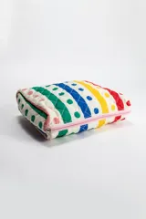 Necessaire de forma rectangular con diseño acolchado y cierre superior. Presenta un estampado de rayas diagonales en colores vibrantes como rojo, amarillo, azul y verde sobre fondo blanco, con detalles de lunares.