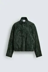 Cazadora regular fit de piel con acabado en ante color verde oscuro, de la colección especial Gabriel Azevedo x ZARA. Cuenta con cuello subido, manga larga, bolsillos de vivo en la cadera, bolsillo interior y bajo acabado con elástico. Cierre frontal con cremallera oculta por solapa con botones a presión.