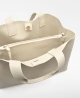 Bolso shopper horizontal negro de piel sintética, con dos compartimentos, cierre magnético y bolsillo interior con cremallera. Cuenta con asa de mano y correa larga regulable y extraíble, además del logo grabado en el frente.