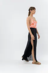 Pantalón ancho de gasa liviana color blanco, con cintura elástica y aberturas laterales decoradas con pompones.