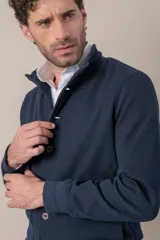 Campera azul marino tejida en algodón, con cuello mao, cierre frontal con botones, dos bolsillos de parche con botón en el frente y puños tejidos.