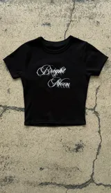 Remera crop negra de manga corta, con cuello redondo y estampado frontal con el texto "Bright Moon" en efecto difuminado.